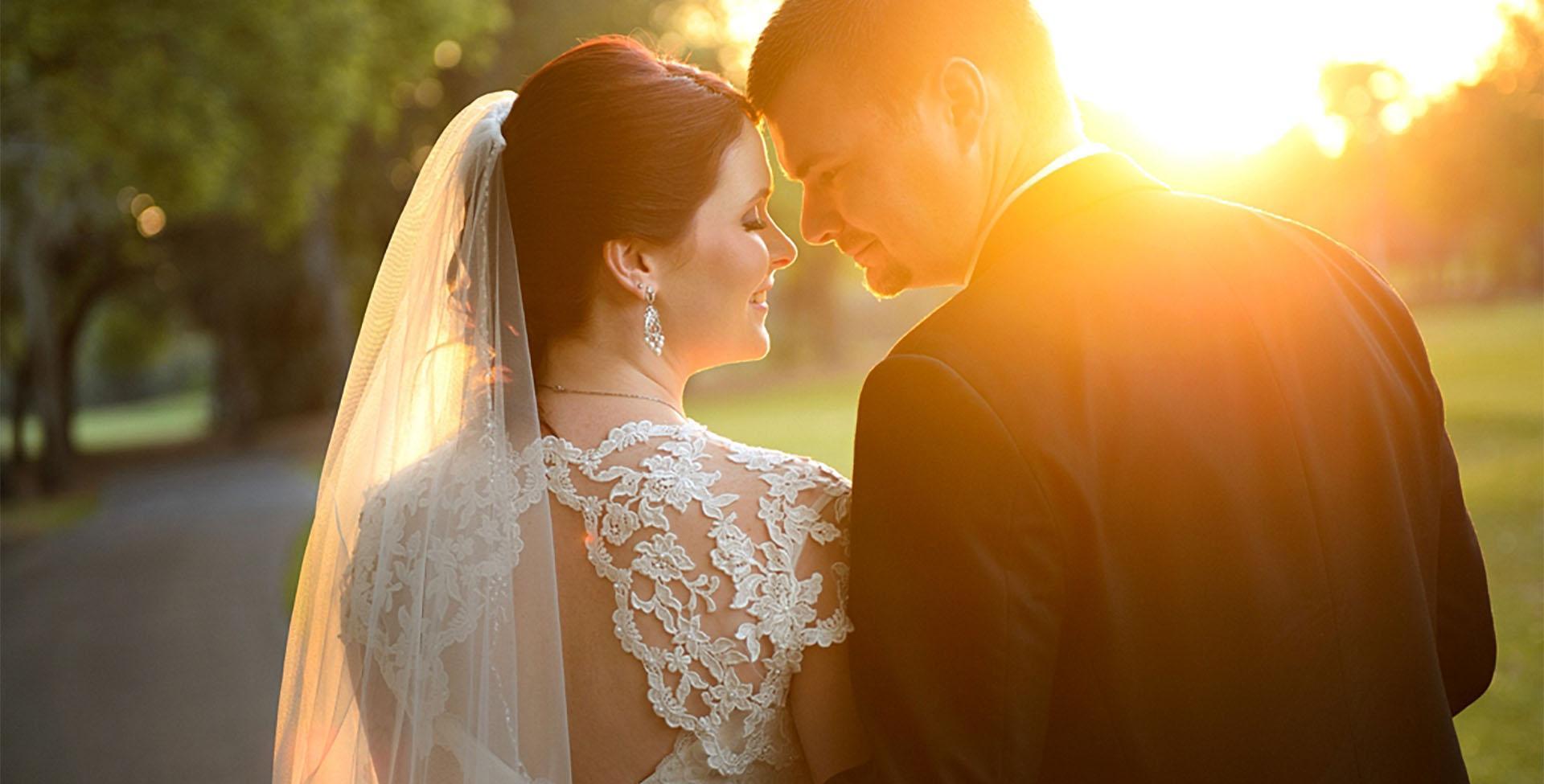 A bride and groom with a sunset behind them