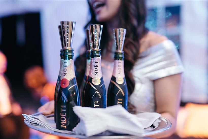 A woman carrying multiple bottles of alcohol