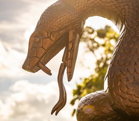 A statue of a snake with the golf course in the background