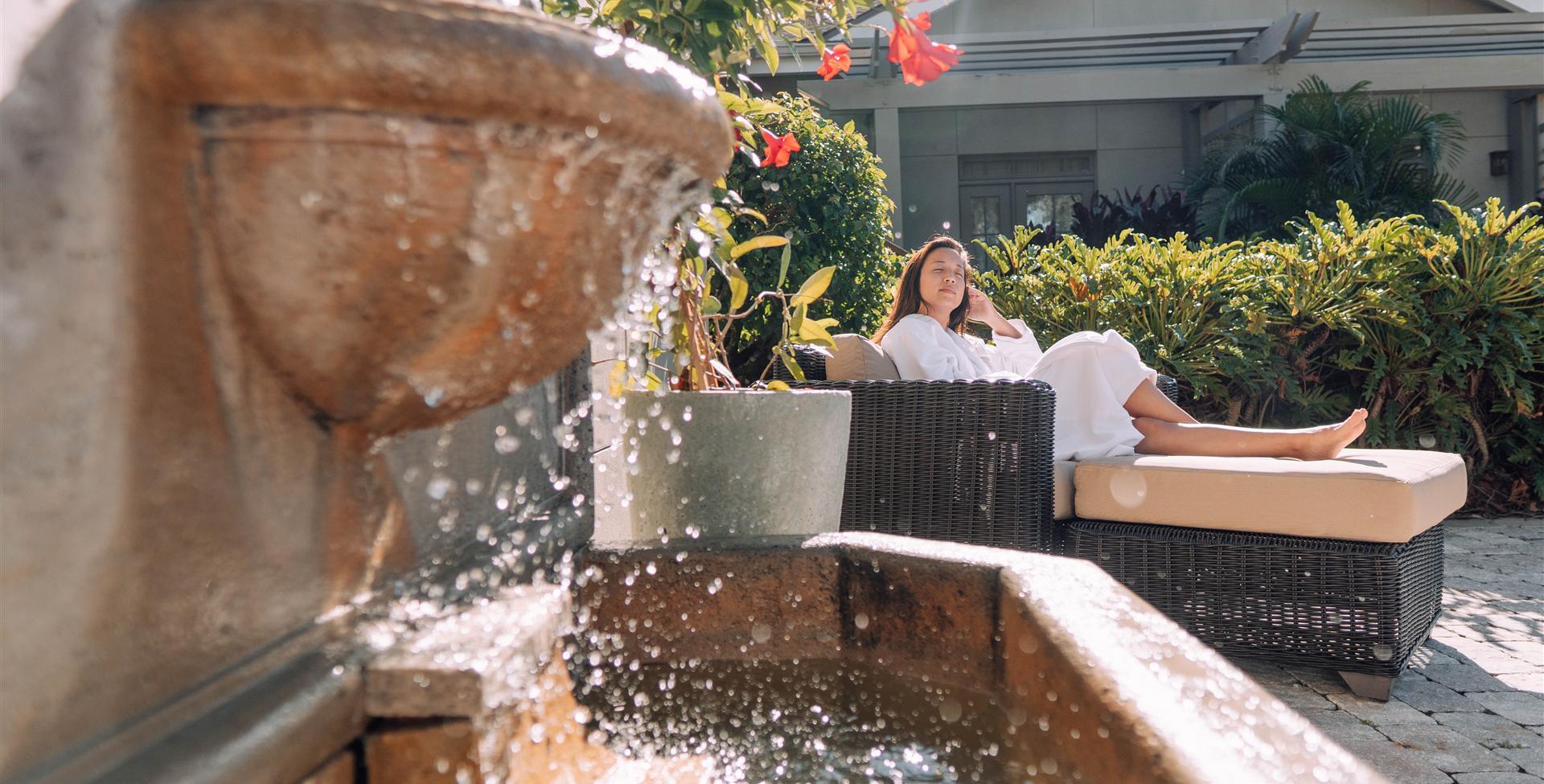 A lady sitting in a robe by water fountain