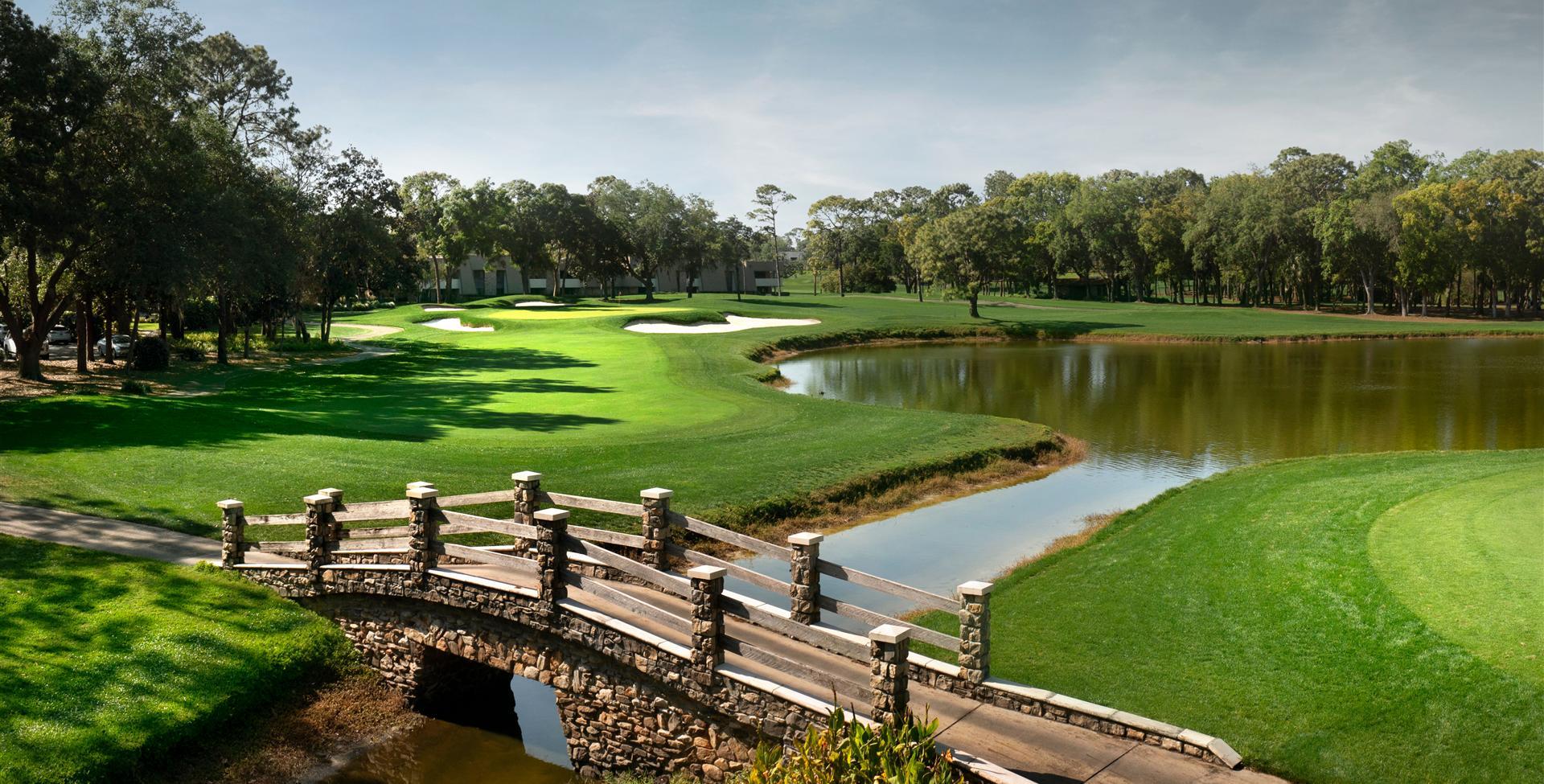 A river running through the golf course with a bridge going over it