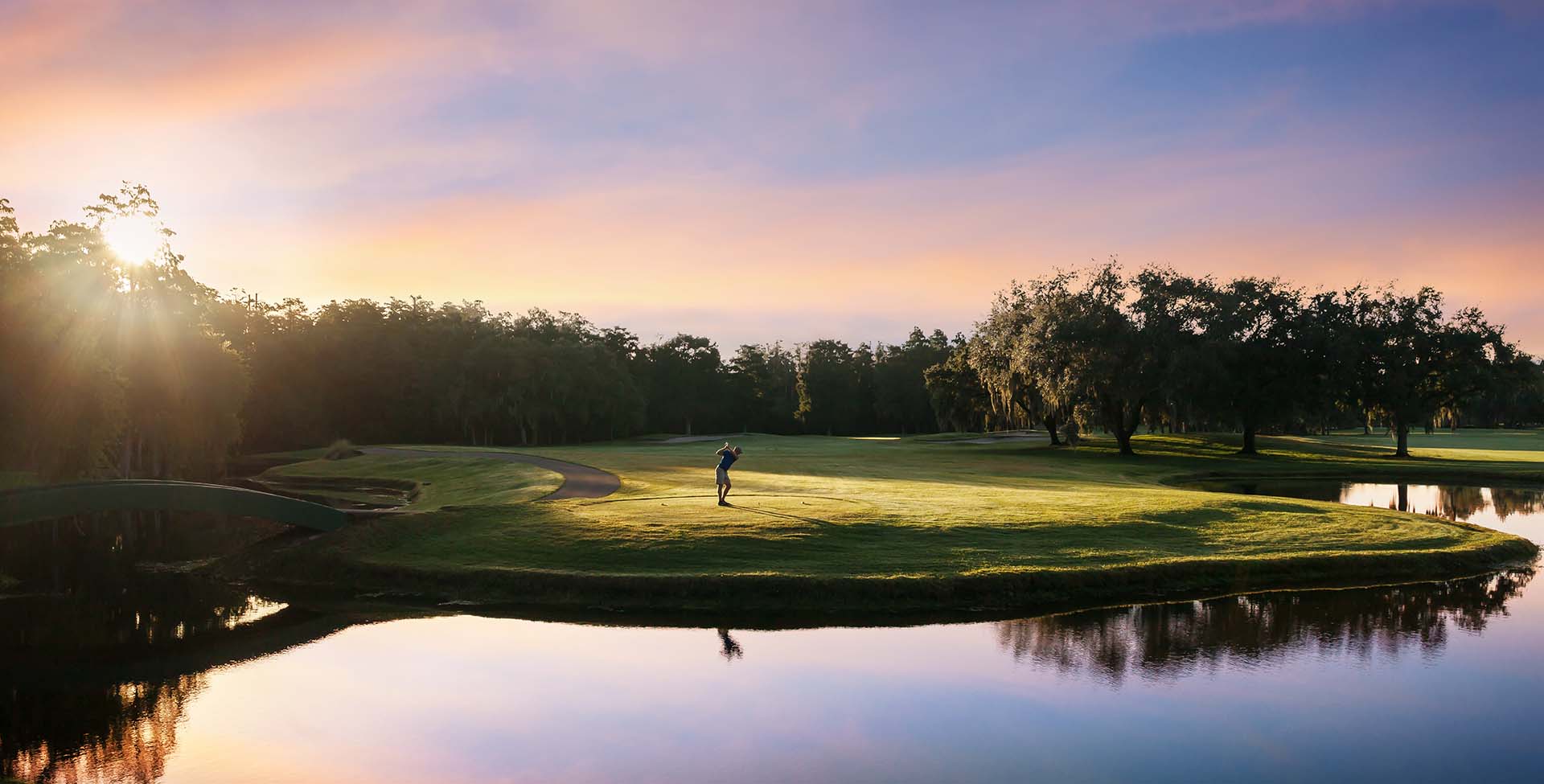 Golfer Teeing Off at Sunset Near the Water