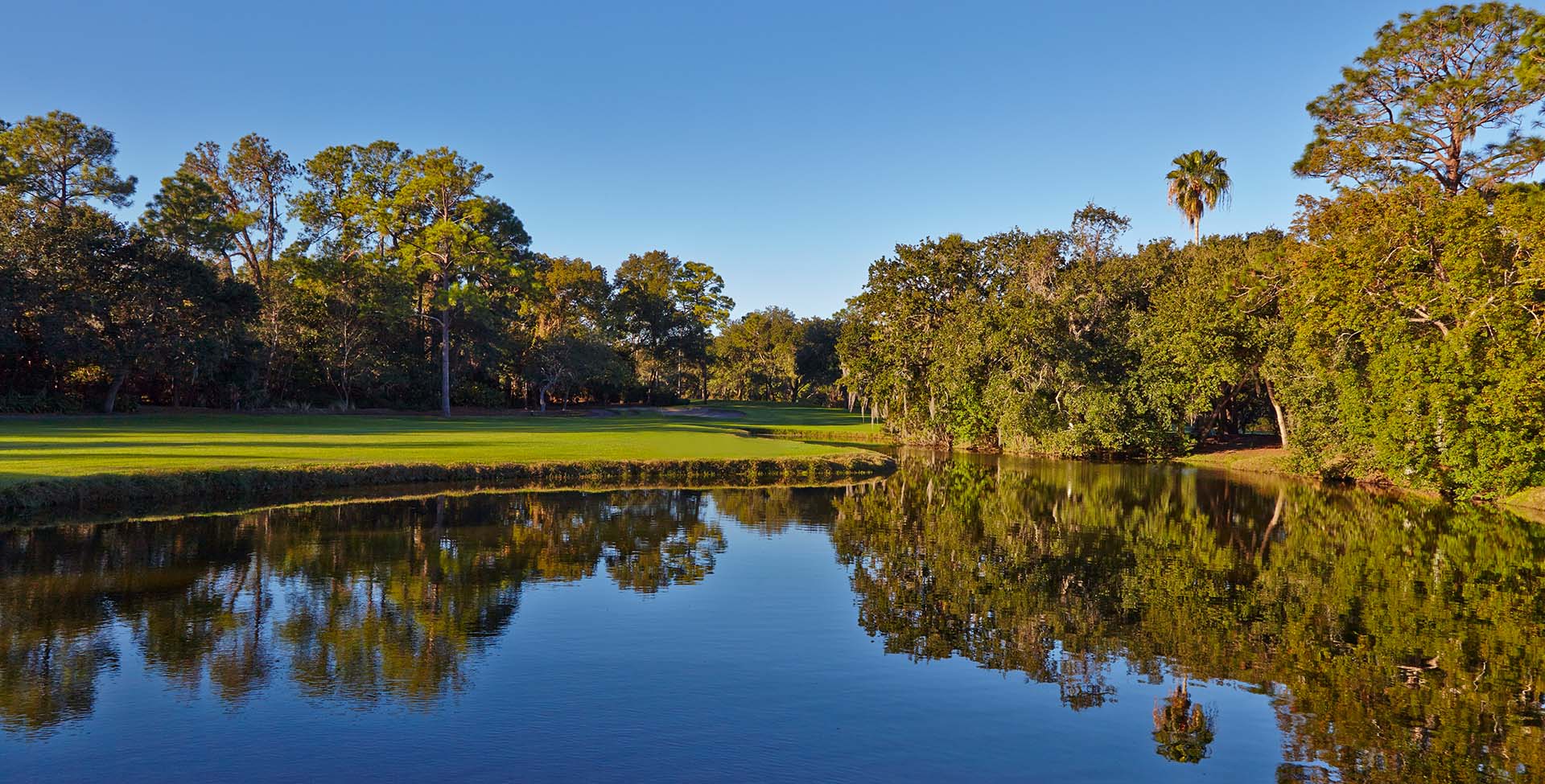 A lake with a green field to the side of it